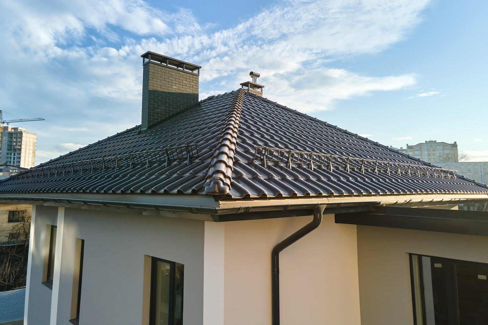 Closeup of house roof top covered with ceramic shingles with gutter pipes