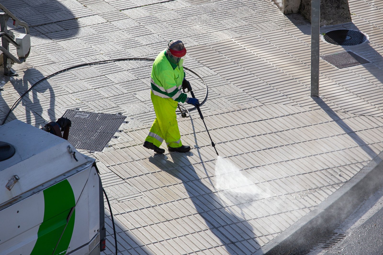 Worker cleaning a sidewalk with high pressure water jet machine